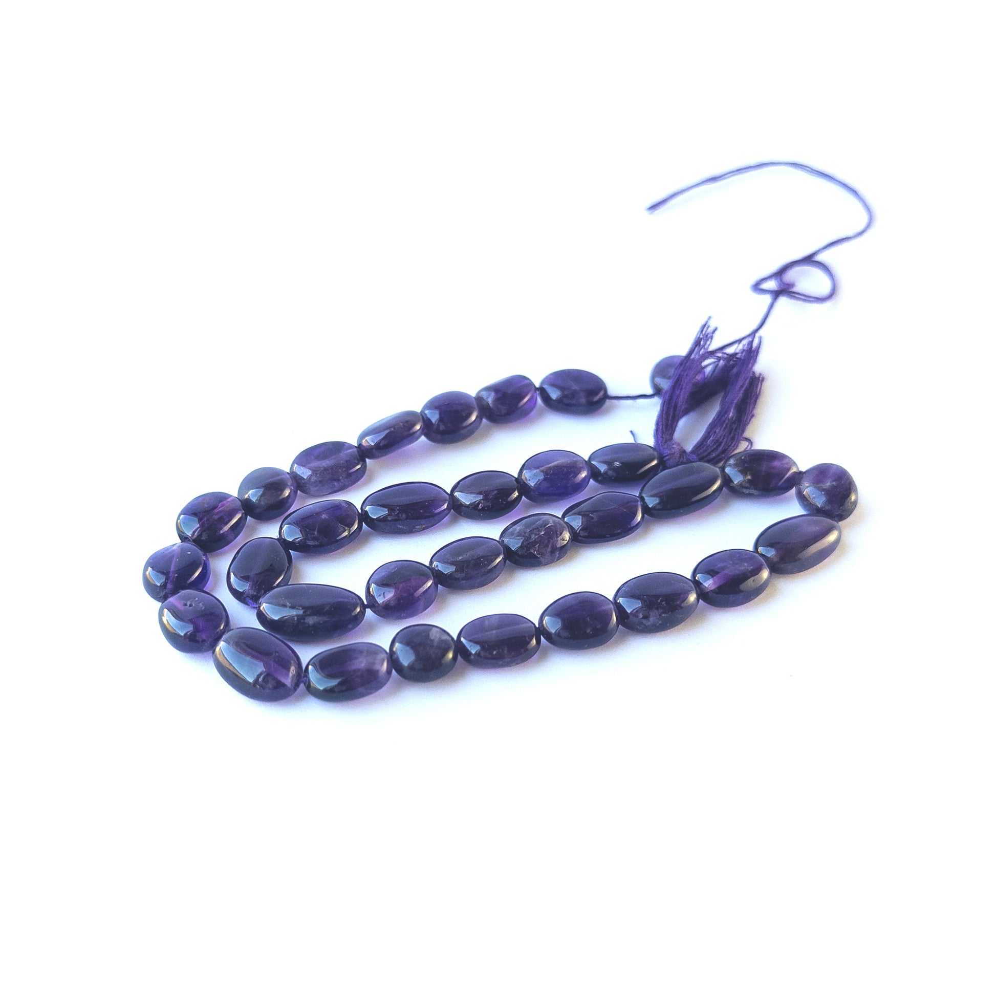 Handmade jewellery components featuring natural amethyst smooth oval beads in a neatly aligned strand.