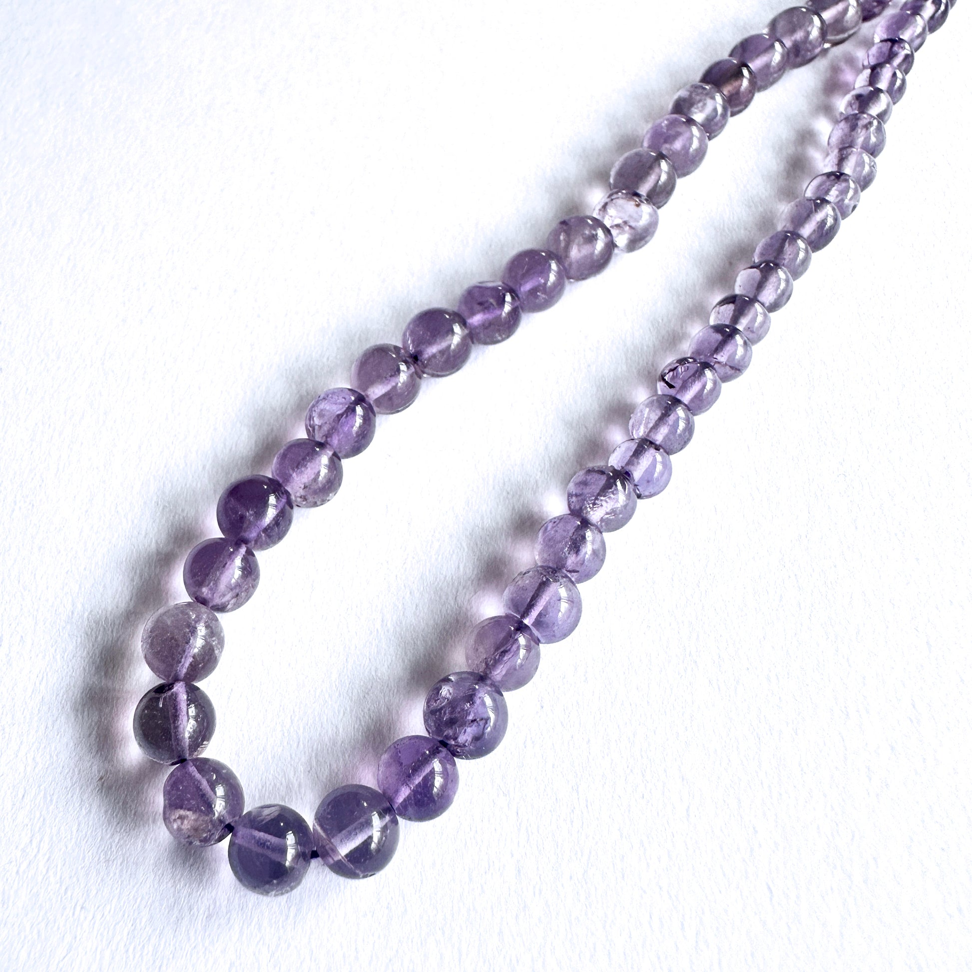 Close-up of Amethyst beads showcasing their glossy surface and rich colour.