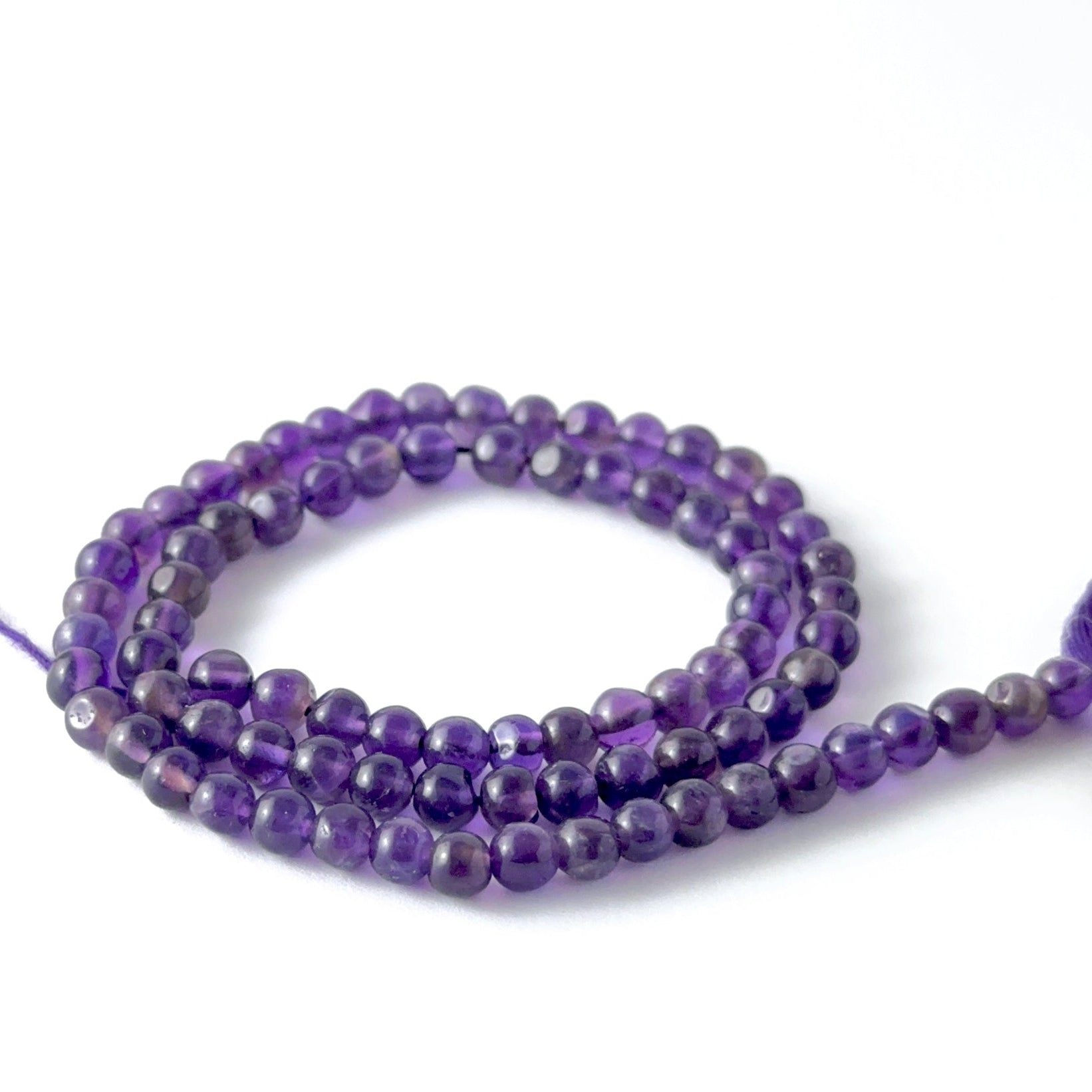 Smooth round Amethyst stone beads arranged neatly, highlighting their polished finish and handmade jewellery component quality.