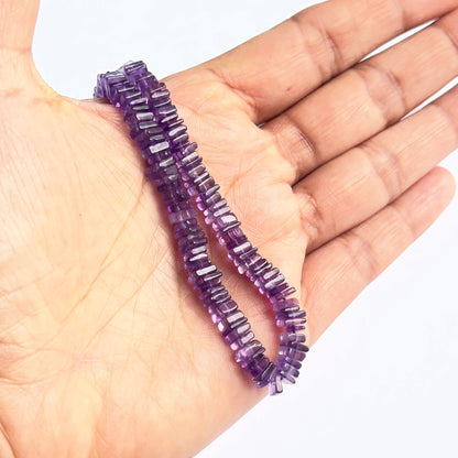 A person holds delicate strands of amethyst smooth square heishi beads, showcasing their smooth design.