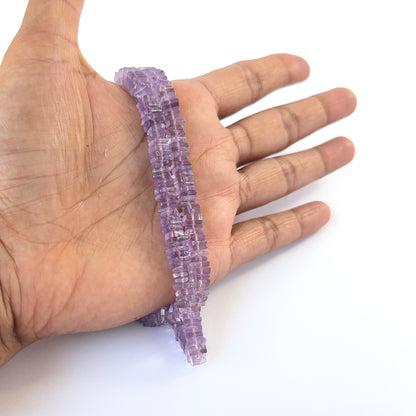 A person holds delicate strands of Amethyst smooth square heishi beads, showcasing their polished design.