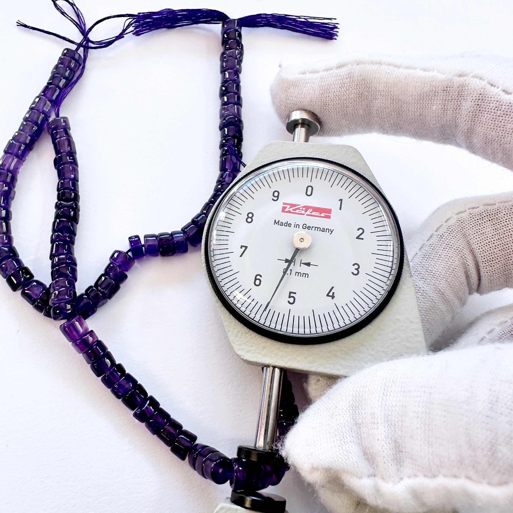 A dial gauge measures the Amethyst smooth wheel 5.5mm gemstone.