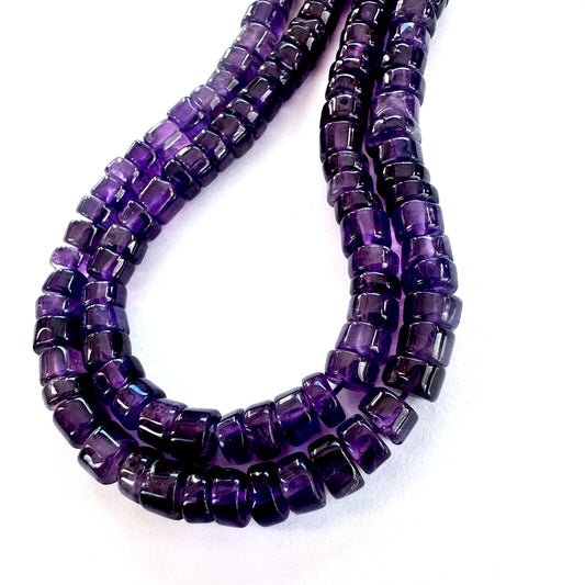 Close-up of Amethyst smooth wheel beads with vibrant purple tones and glossy surface.