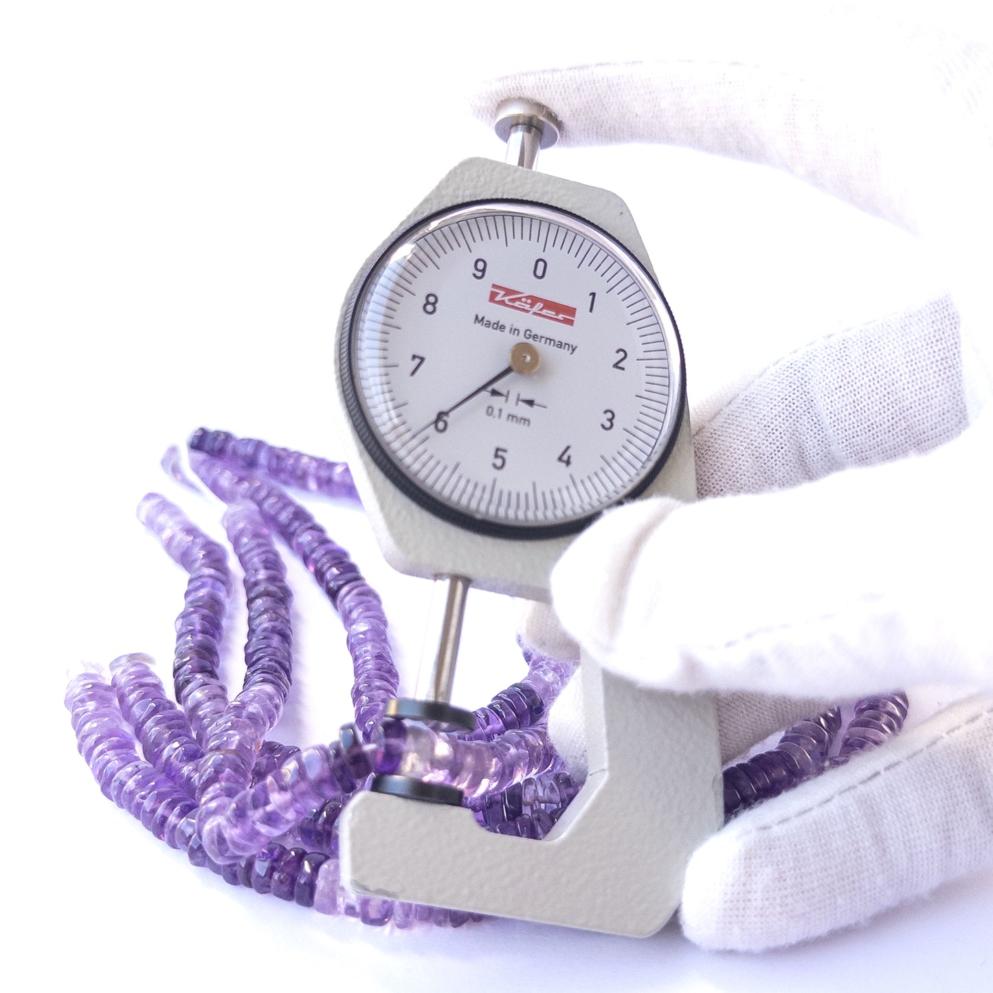 A dial gauge measures the Amethyst smooth wheel 6–6.3mm gemstone.