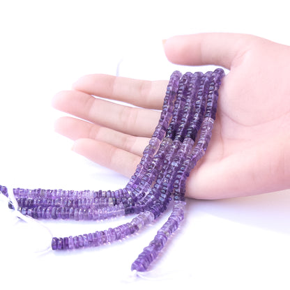 A person holds delicate strands of Amethyst beads, showcasing their smooth wheel design.
