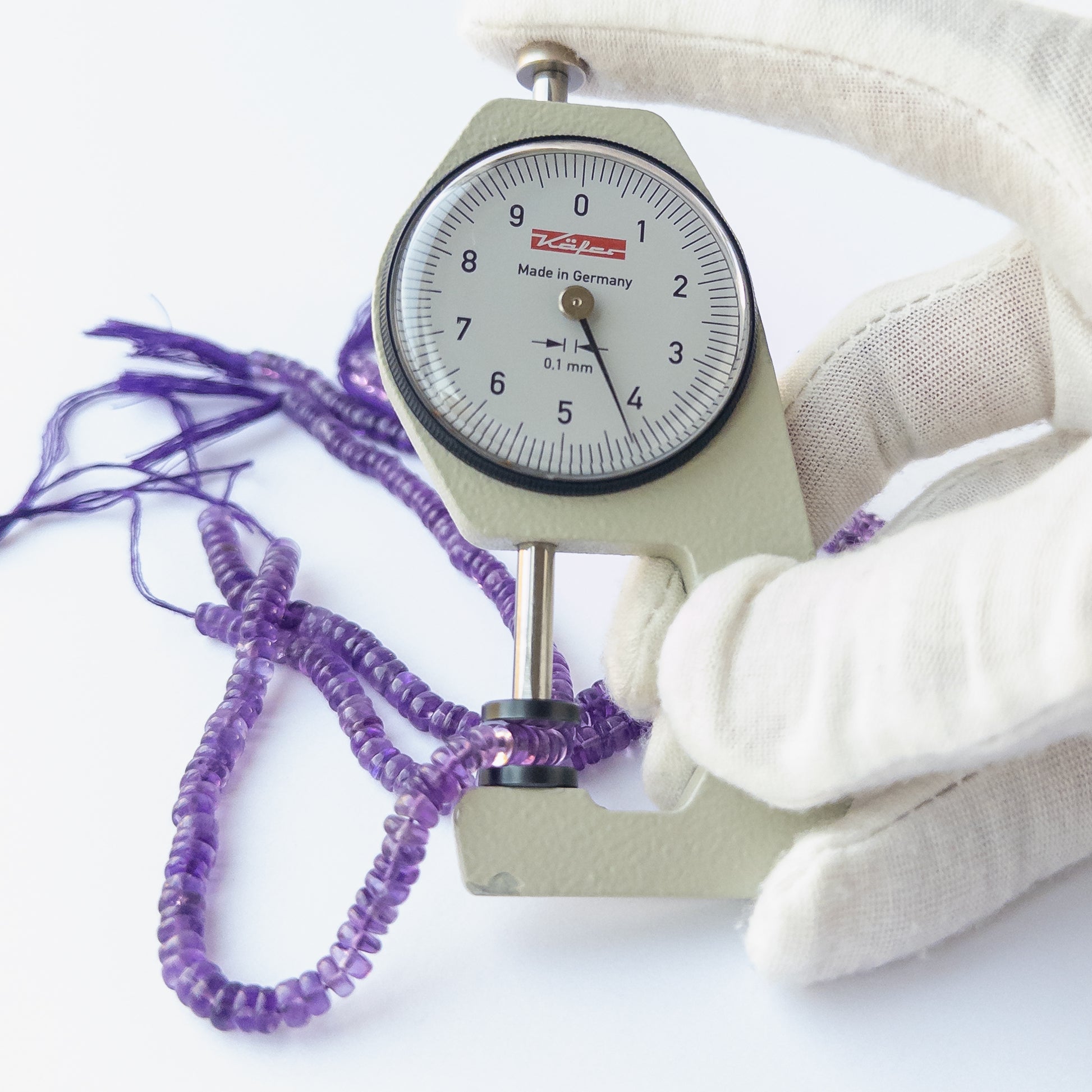 A dial gauge measures the Amethyst smooth wheel 4–5mm gemstone.