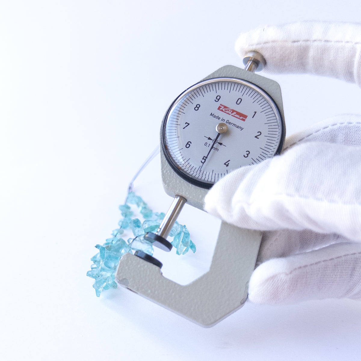A dial gauge measures the Apatite drilled rough 4–5mm gemstone.