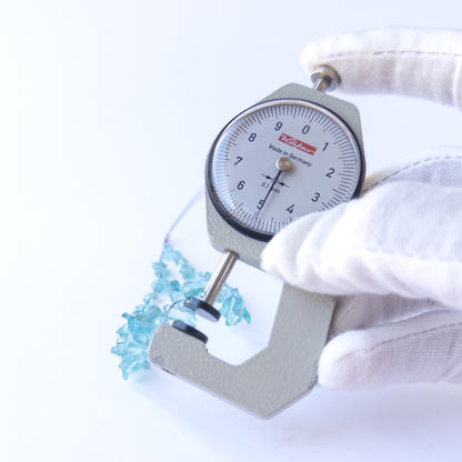 A dial gauge measures the Apatite drilled rough 4–5mm gemstone.