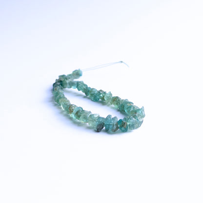 Apatite drilled rough beads arranged in a strand showing vivid blue tones and raw crystal texture.