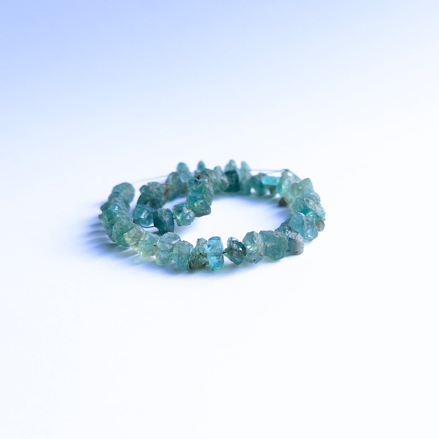 Blue Apatite rough beads arranged neatly, highlighting their earthy finish and 6–7mm size.