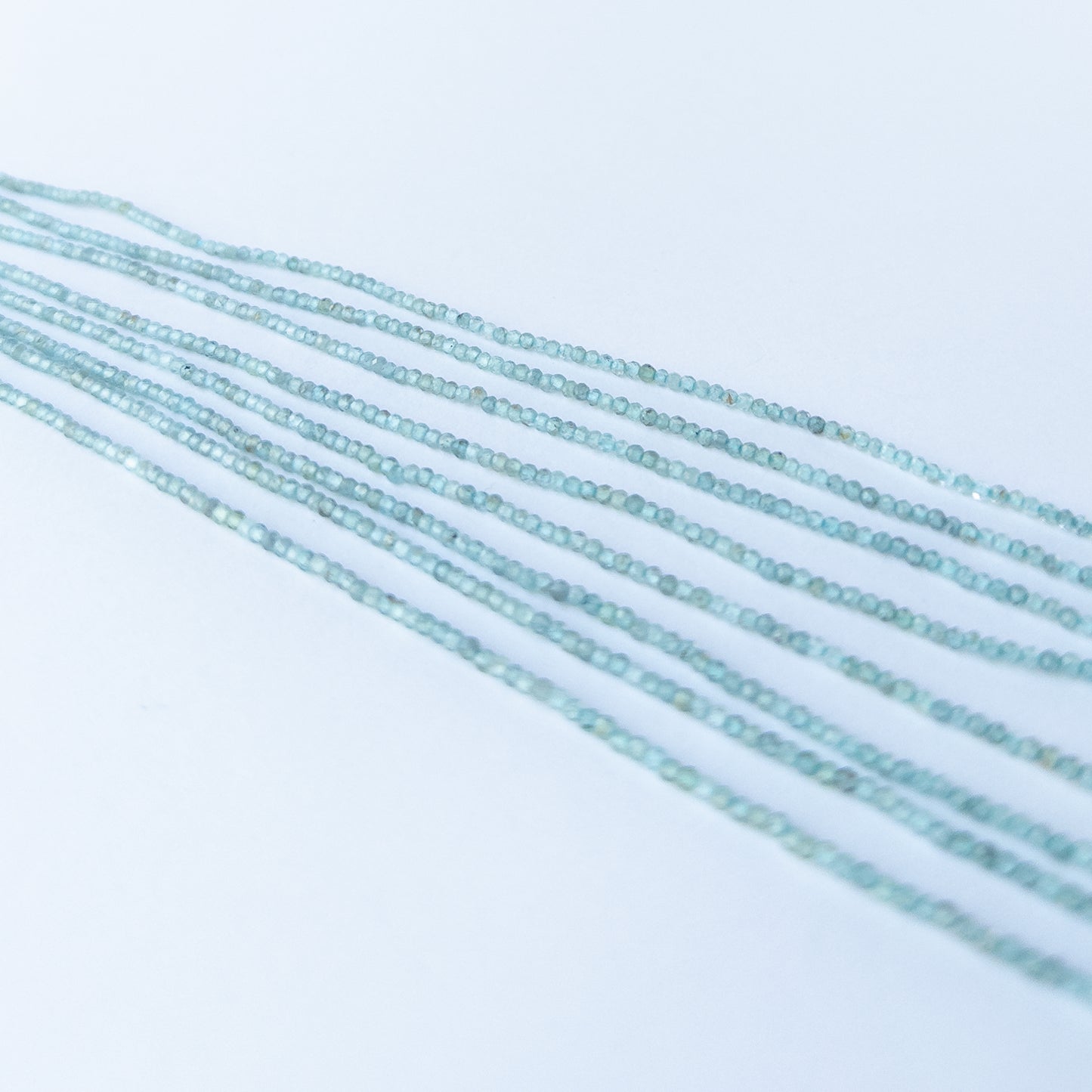 Close‑up of Apatite faceted rondelle beads showing clarity, sparkle and premium gemstone bead craftsmanship.