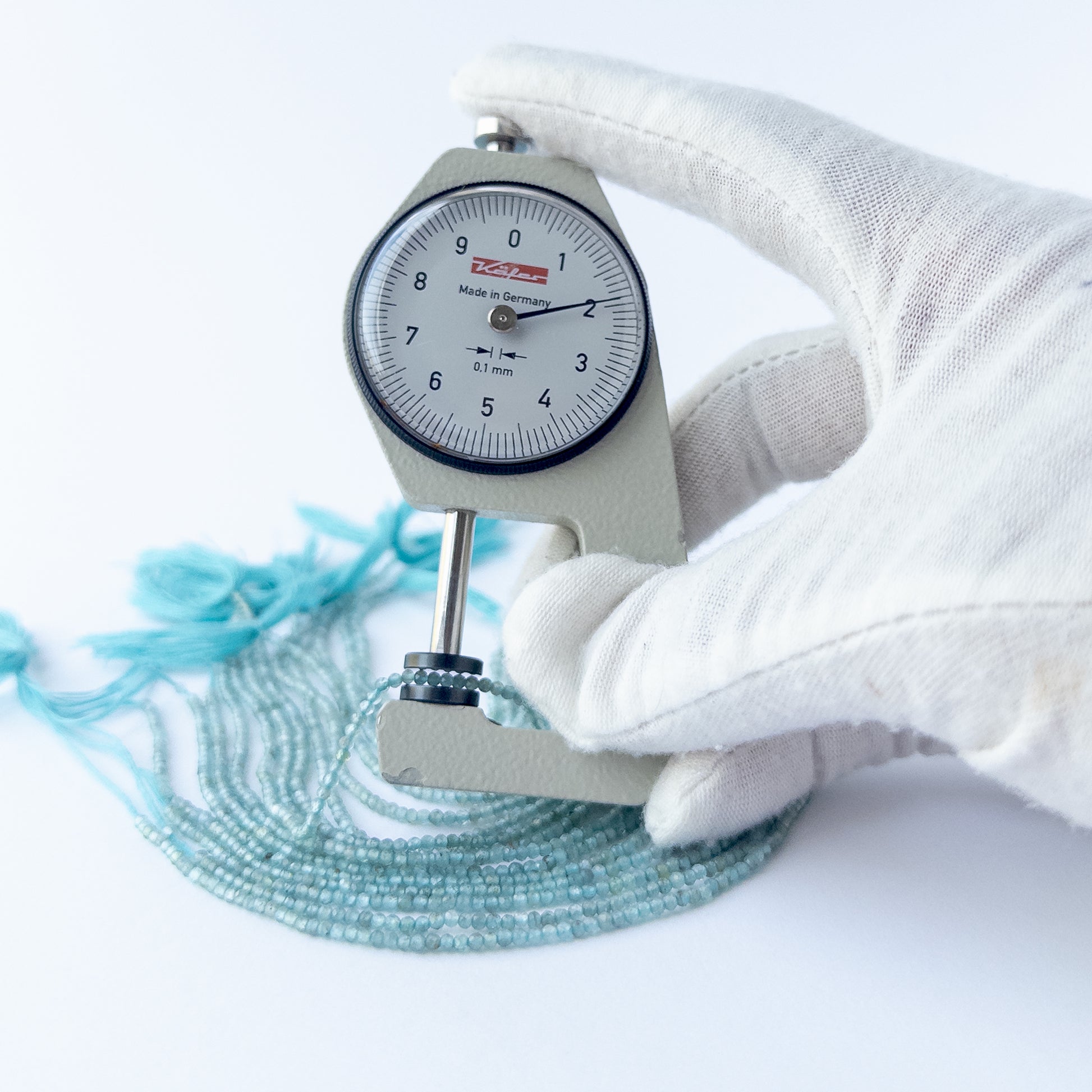 A dial gauge measures the Apatite faceted rondelle 2mm gemstone.