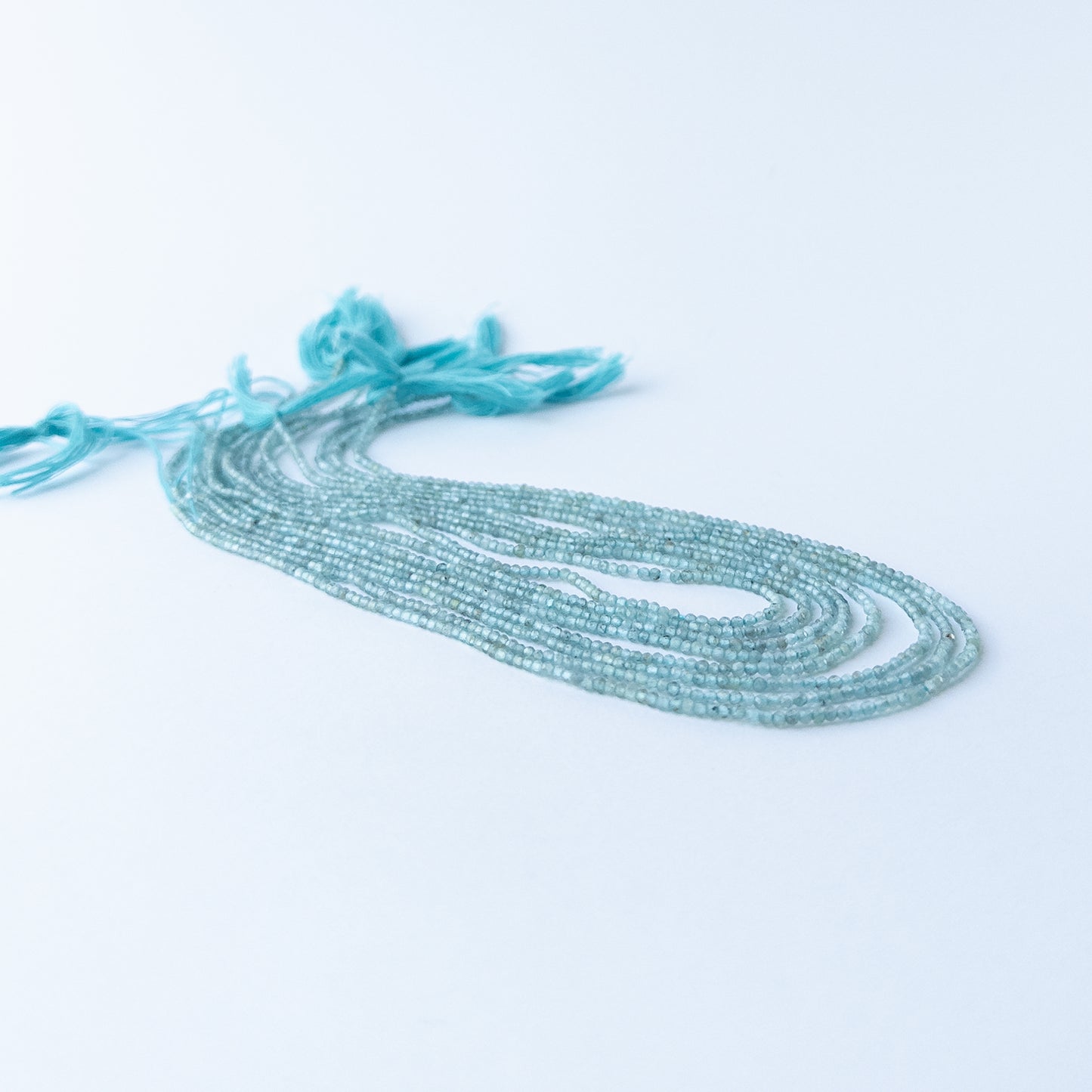 Handmade jewellery components featuring tiny Apatite rondelle beads with polished facets and natural blue glow.