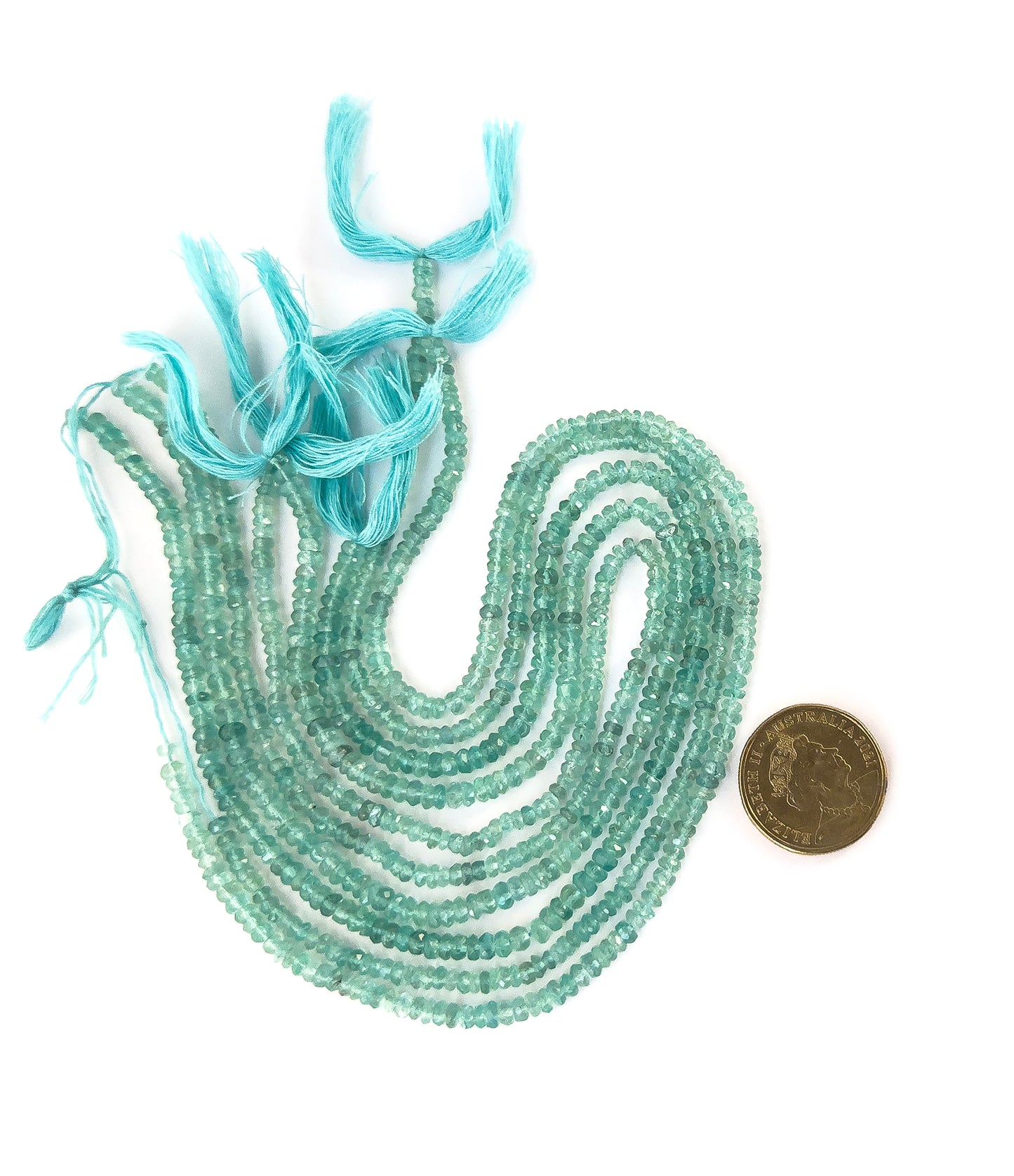 A coin is placed near Apatite faceted rondelle beads to show the 3.5–4.5mm size range.