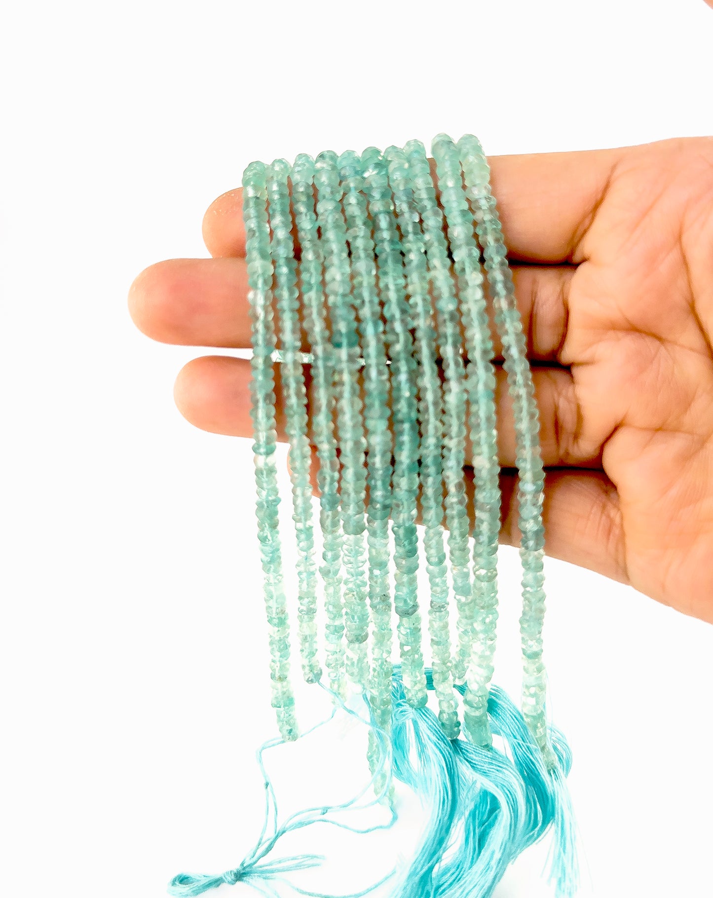 A person holds Apatite faceted rondelle beads, showing their faceted design and vivid blue colour.