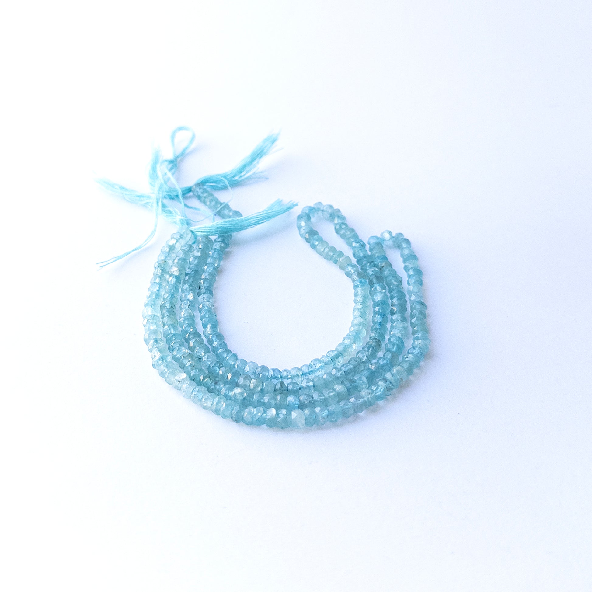 Genuine Apatite gemstone beads displaying vivid aqua tones, polished facets, and a neatly arranged 32cm strand for jewellery design.