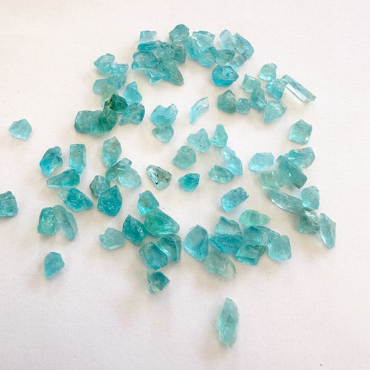 Apatite rough cut beads in blue-green tones arranged in a loose cluster.