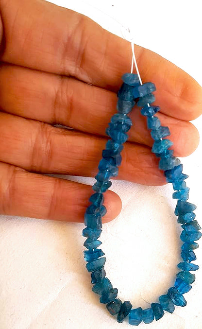 A person holds delicate strands of Apatite beads, showcasing their natural design.