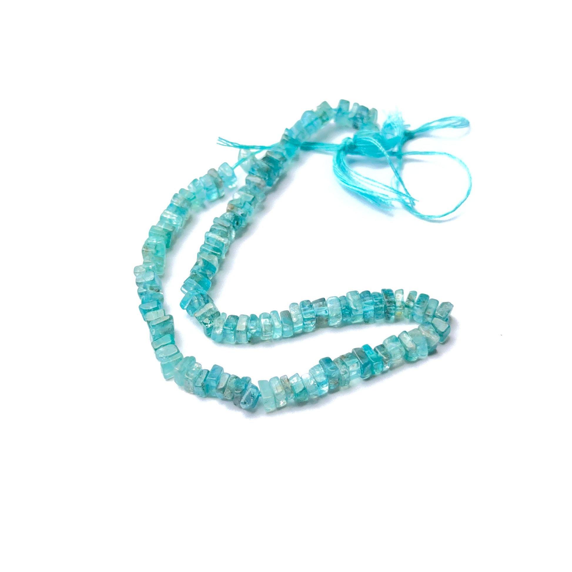 A person holds delicate strands of Apatite beads, showcasing their smooth design.