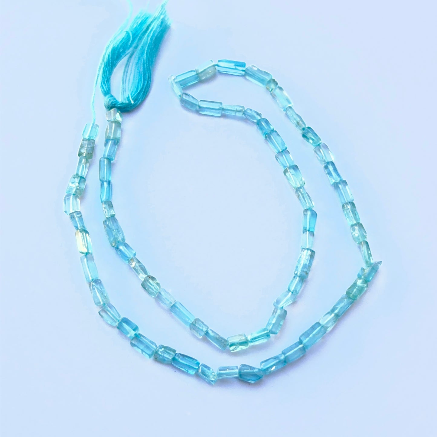 Apatite smooth rectangle beads aligned on a strand highlighting clarity, colour and consistent 3mm sizing.