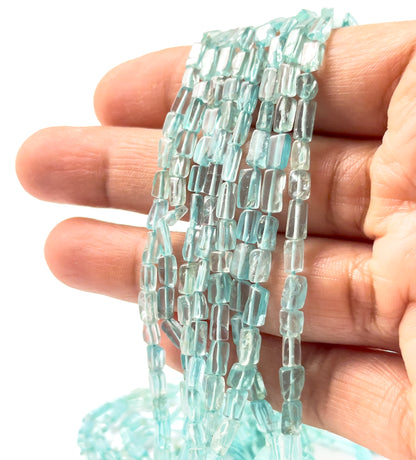 A person holds Apatite smooth rectangle heishi beads, showing their geometric design and vivid colour.