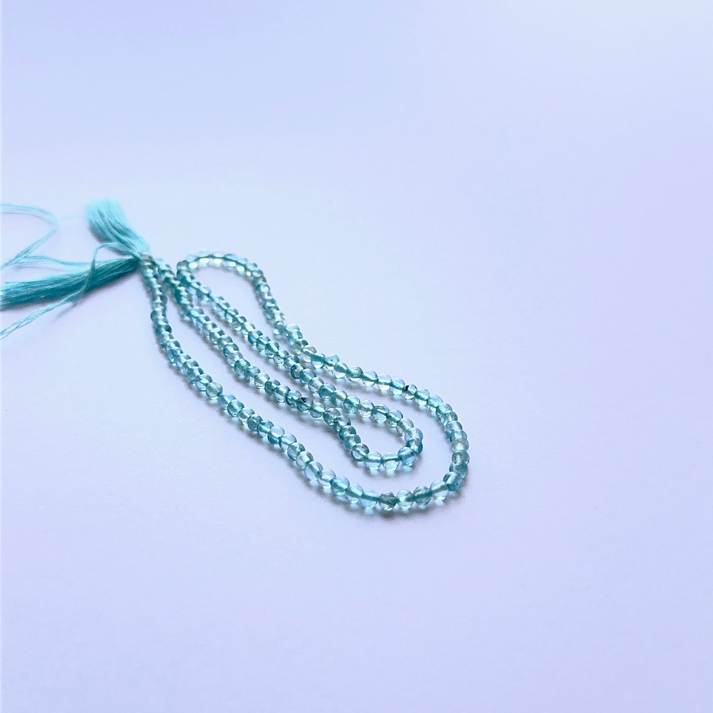 Detailed view of premium Apatite stone beads showing uniform 2.9mm shape, soft glow and vibrant blue colour.