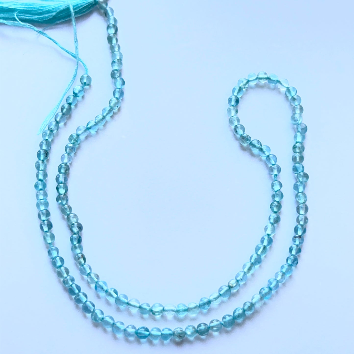 Apatite smooth round beads aligned on a strand highlighting clarity, shine and consistent sizing.