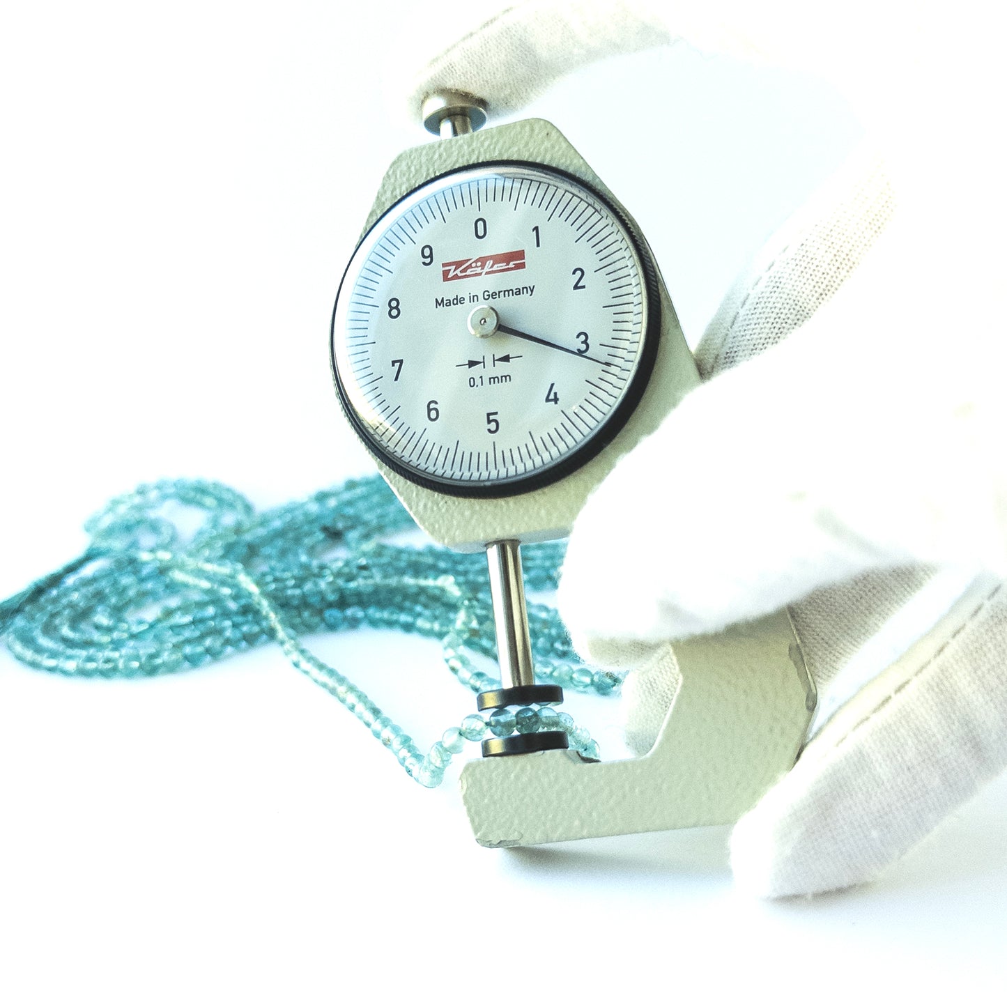 A dial gauge measures the Apatite Smooth Round 3.4–3.6mm gemstone.