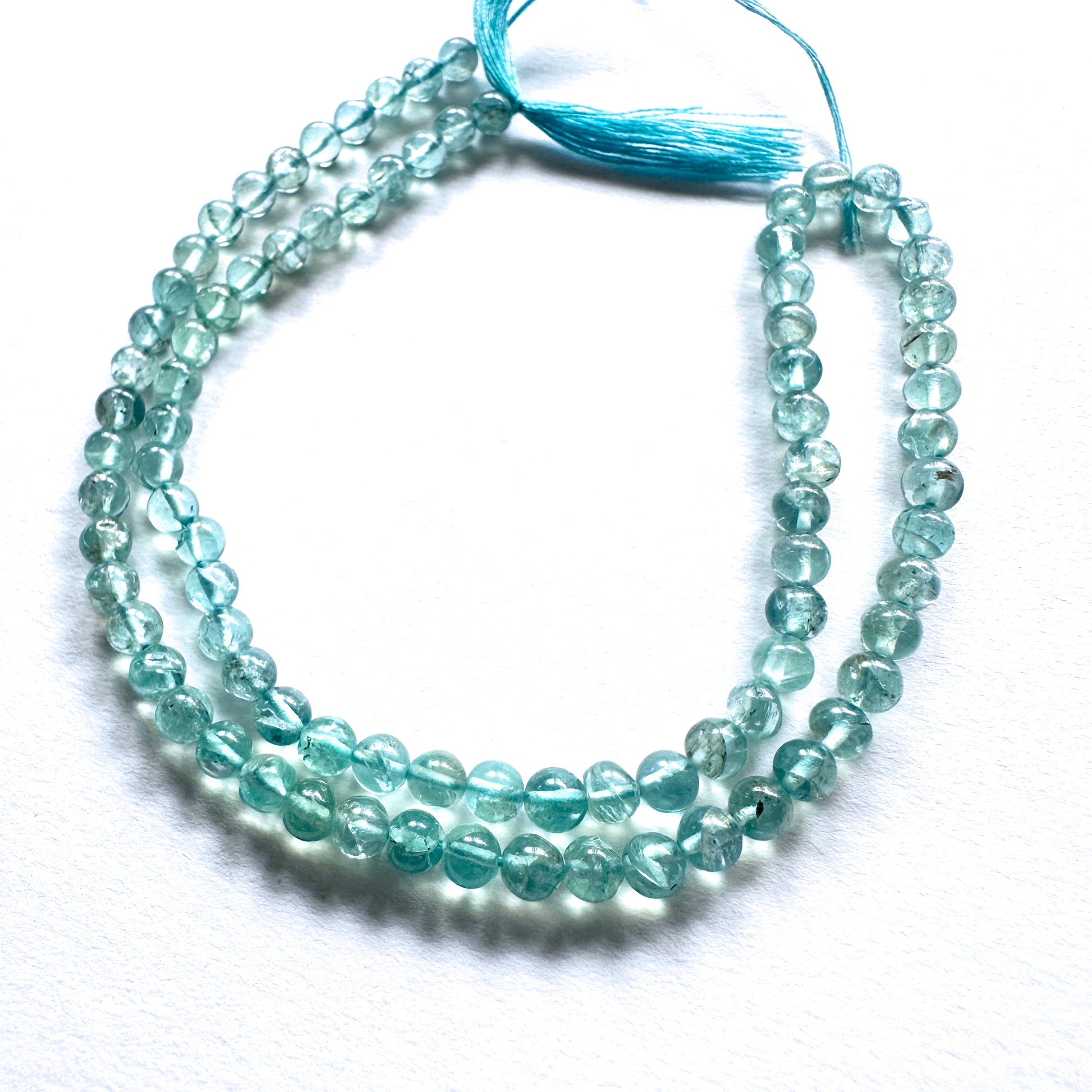 Close-up of Apatite beads showcasing their glossy surface and vibrant oceanic colour.