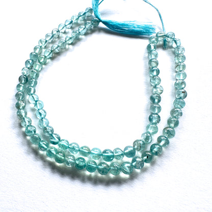 Close-up of Apatite beads showcasing their glossy surface and vibrant oceanic colour.