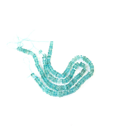 Apatite smooth square heishi gemstone beads in vivid blue tones arranged on a strand for handmade jewellery components.