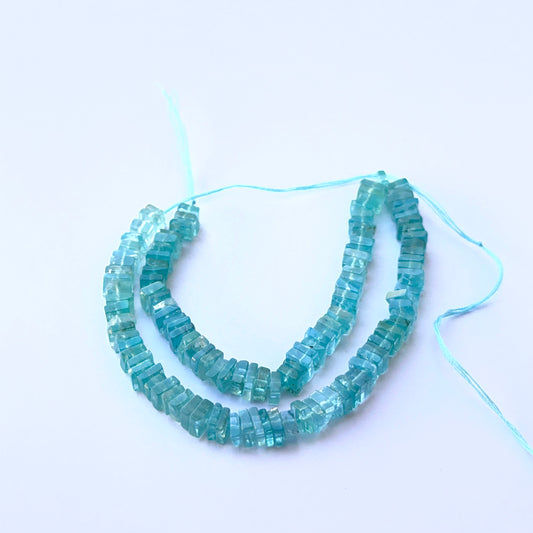 Apatite smooth square Heishi natural gemstone beads in vivid blue tones arranged on a 21cm strand for handmade jewellery components.