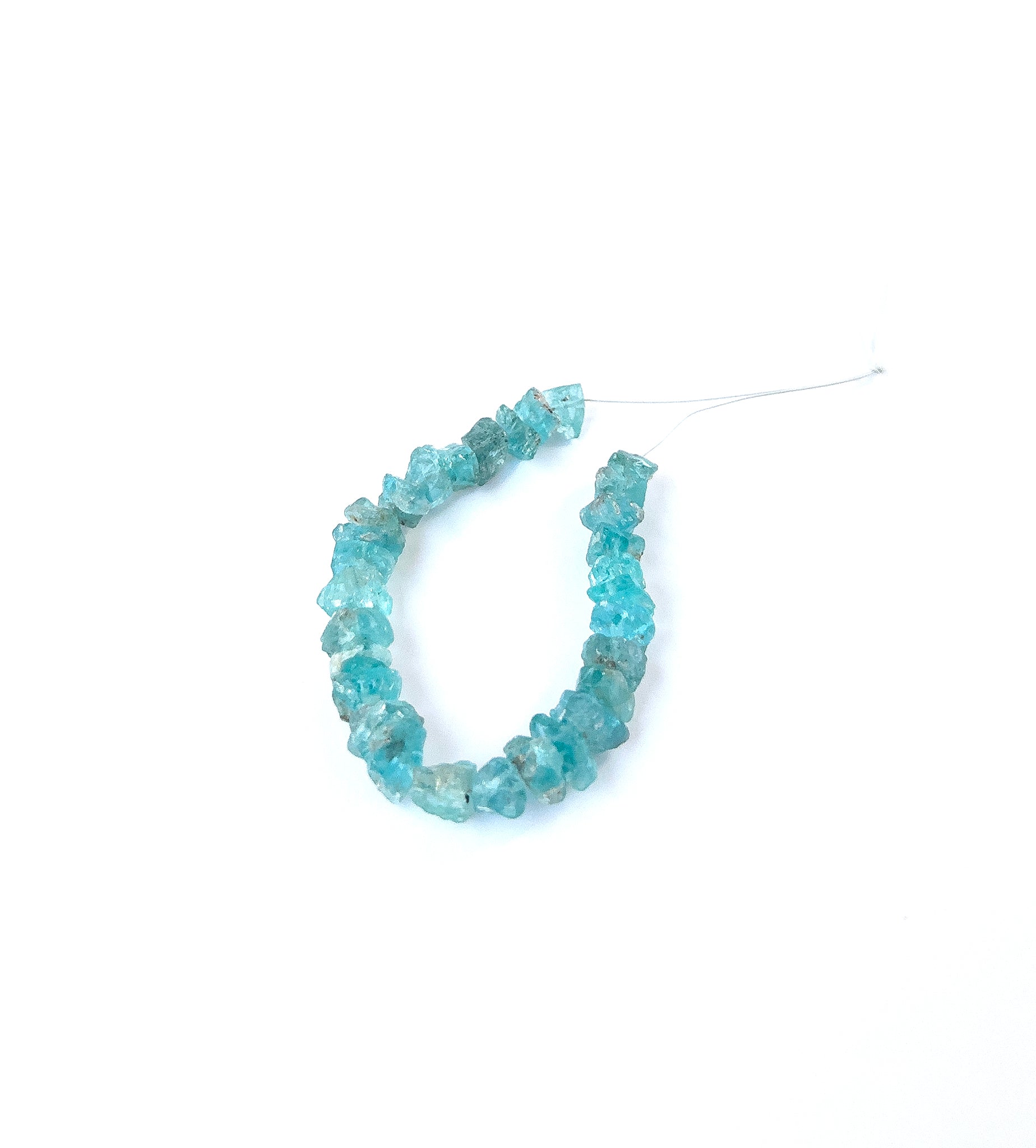 Vivid blue‑green Apatite undrilled rough gemstone pieces arranged on a strand for handmade jewellery components.
