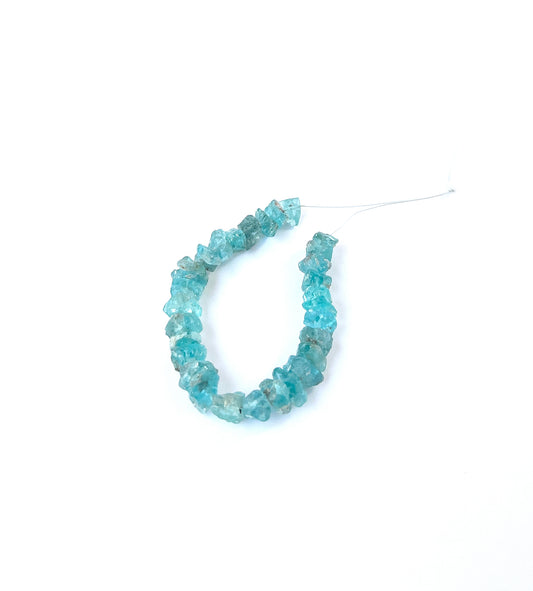 Vivid blue‑green Apatite undrilled rough gemstone pieces arranged on a strand for handmade jewellery components.