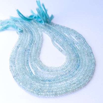 Premium Aquamarine gemstone beads in faceted rondelle cut arranged in strands, showcasing icy blue brilliance for jewellery designers.