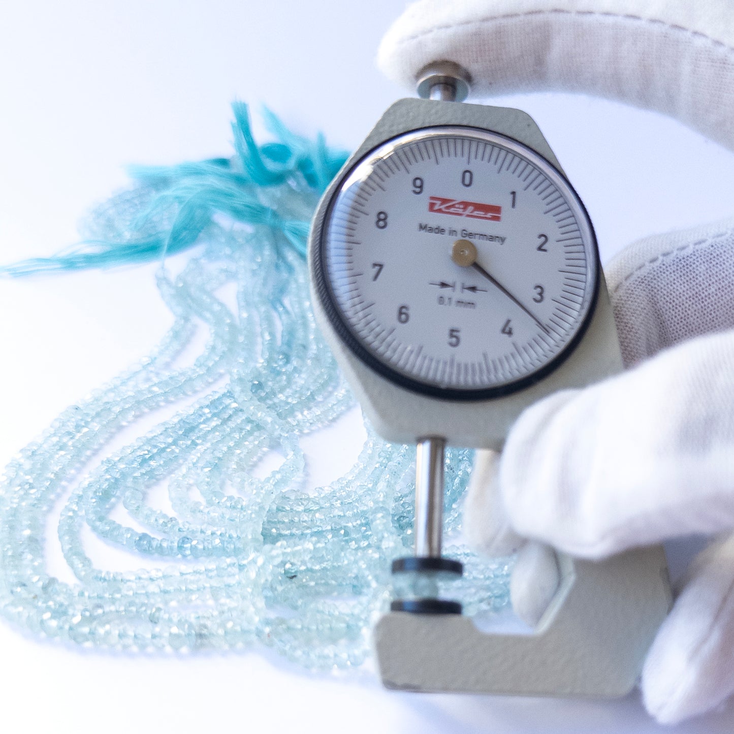 A dial gauge measures the Aquamarine faceted rondelle 2.9–3.7mm gemstone.