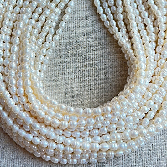 Multiple strands of white pearls on a textured beige background.