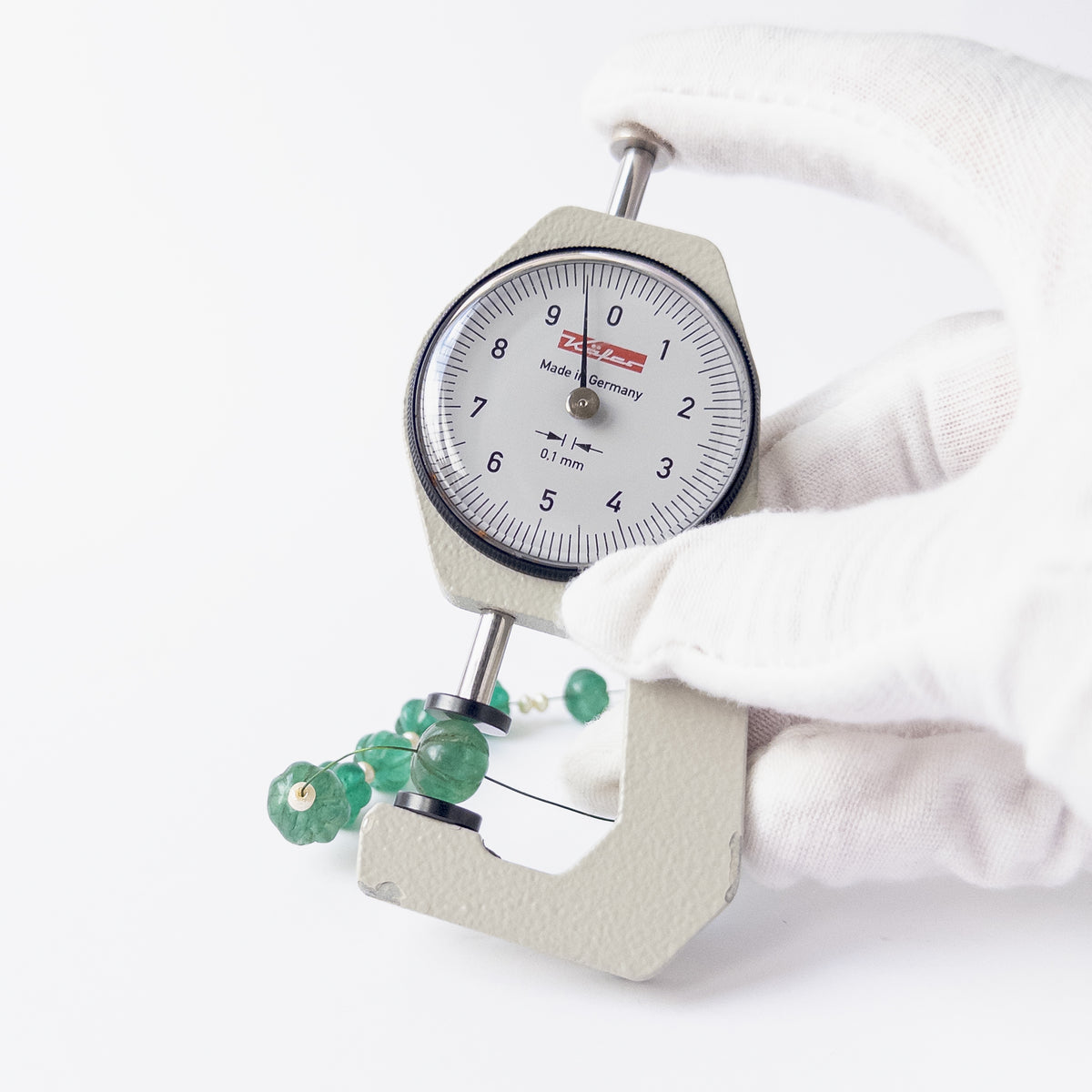 A dial gauge measures the Beryl and Shell Pearl pumpkin cut 8.1–10mm gemstone.