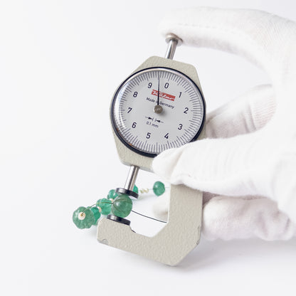 A dial gauge measures the Beryl and Shell Pearl pumpkin cut 8.1–10mm gemstone.