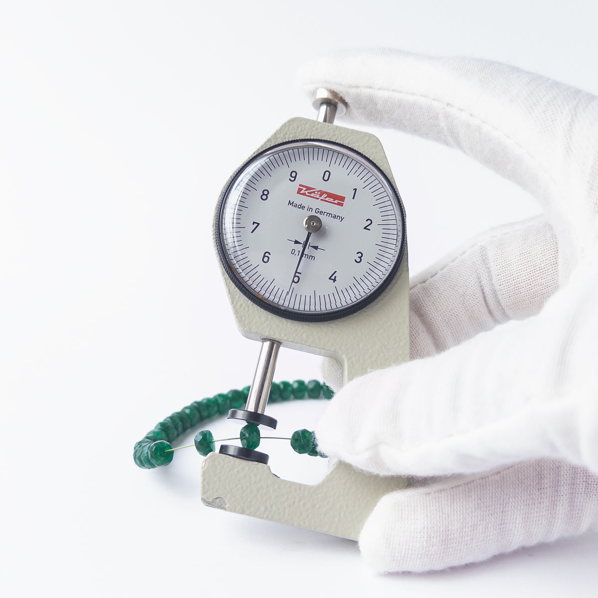 A dial gauge measures the Beryl faceted rondelle 5–5.5mm gemstone.