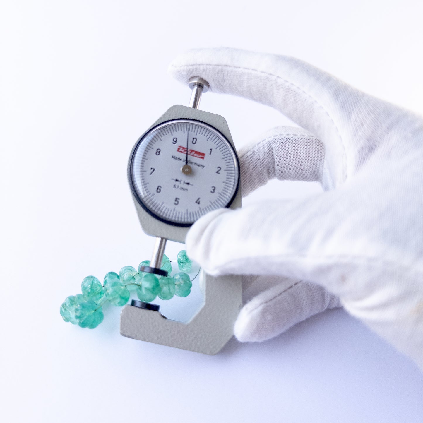 A dial gauge measures the Beryl pumpkin‑cut 9–11.4mm gemstone.