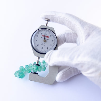 A dial gauge measures the Beryl pumpkin‑cut 9–11.4mm gemstone.