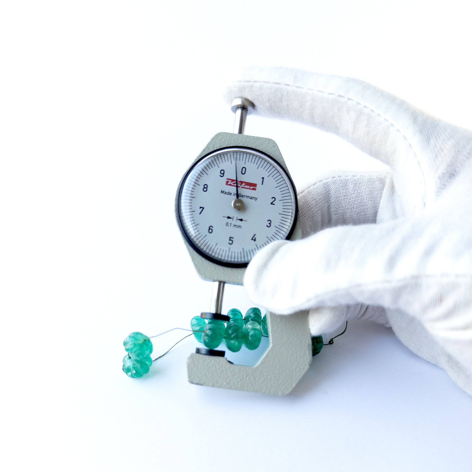 A dial gauge measures the Beryl pumpkin‑cut 9.2–10.5mm gemstone.