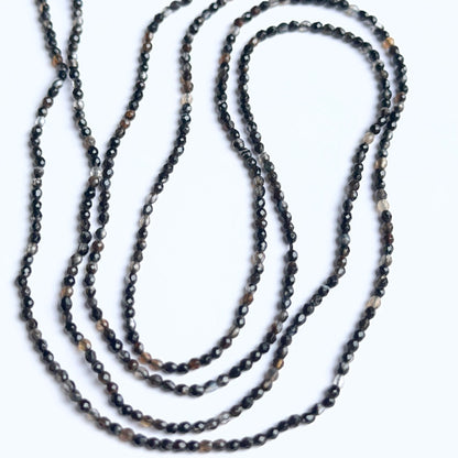 Black fluorite rondelle beads photographed to show their polished finish and suitability for handmade jewellery components.