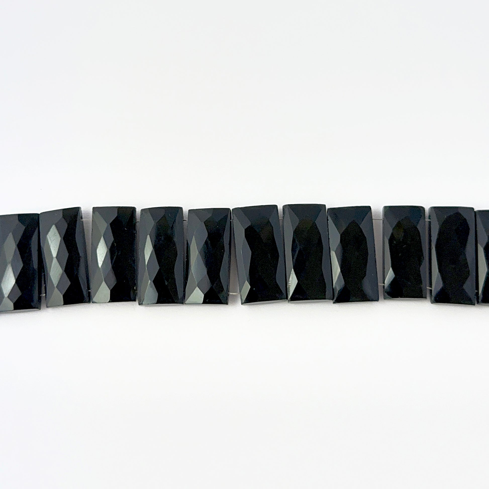 Close view of Black Onyx faceted rectangle stone beads showing cut, clarity and smooth shine for DIY jewellery makers.