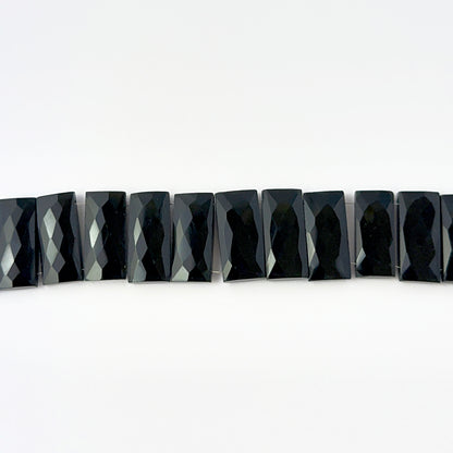 Close view of Black Onyx faceted rectangle stone beads showing cut, clarity and smooth shine for DIY jewellery makers.