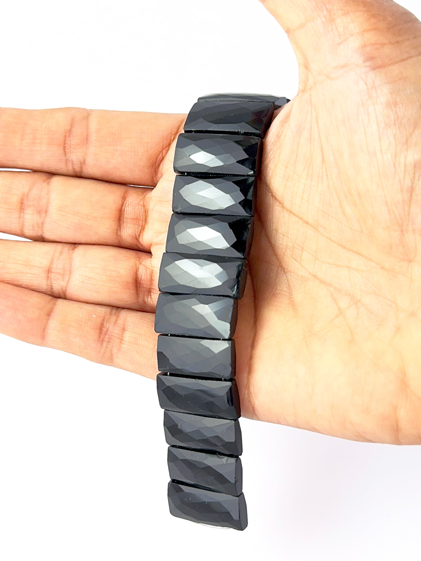 A video person holds delicate strands of Black Onyx beads, showcasing their faceted rectangle design and sparkle.
