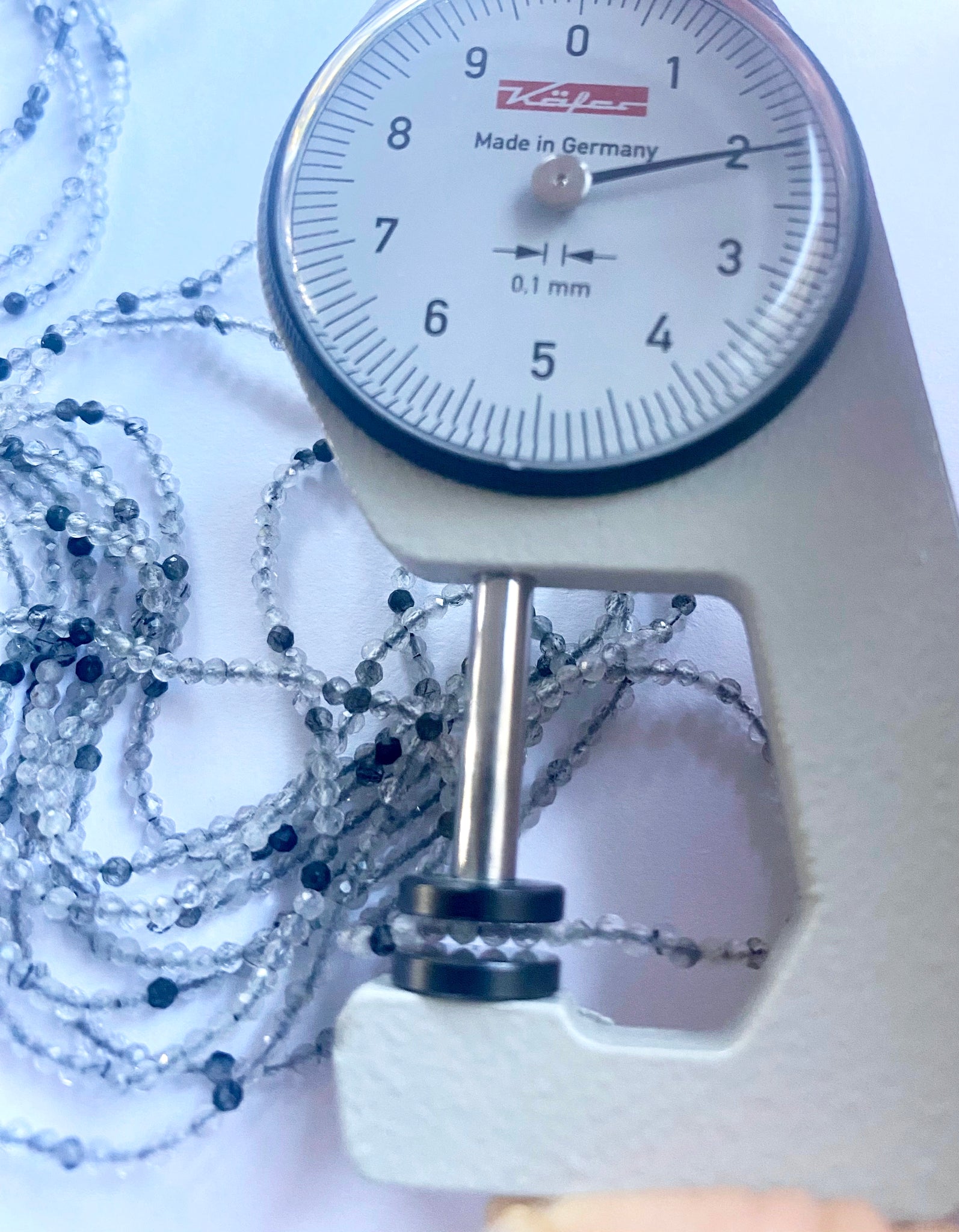A dial gauge measures the black rutile faceted rondelle 2mm gemstone.