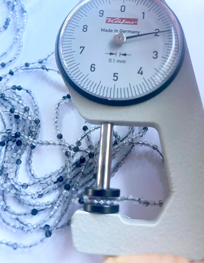 A dial gauge measures the black rutile faceted rondelle 2mm gemstone.