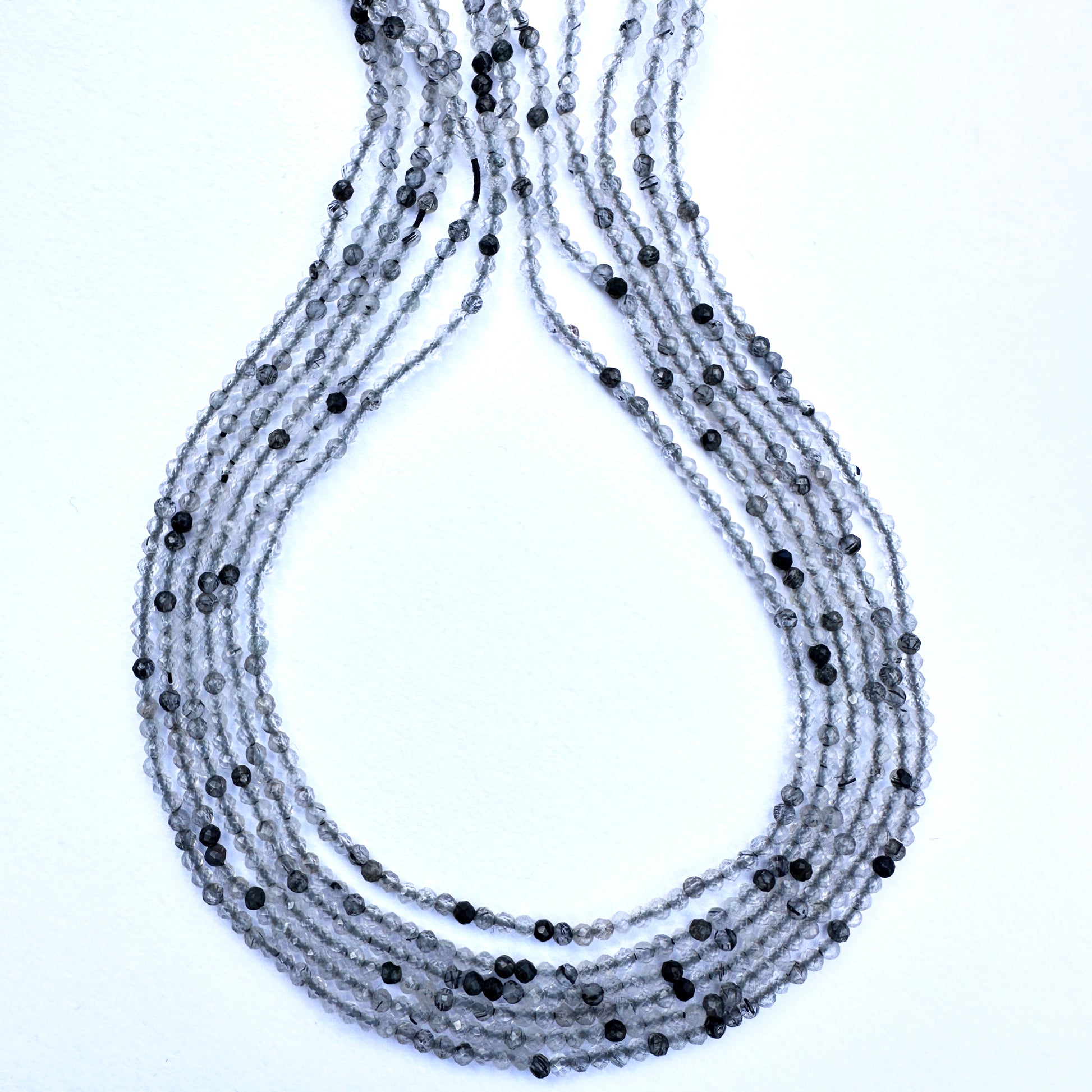 Close-up of black rutile gemstone beads with glossy surface and uniform 2mm sizing for elegant jewellery making.

